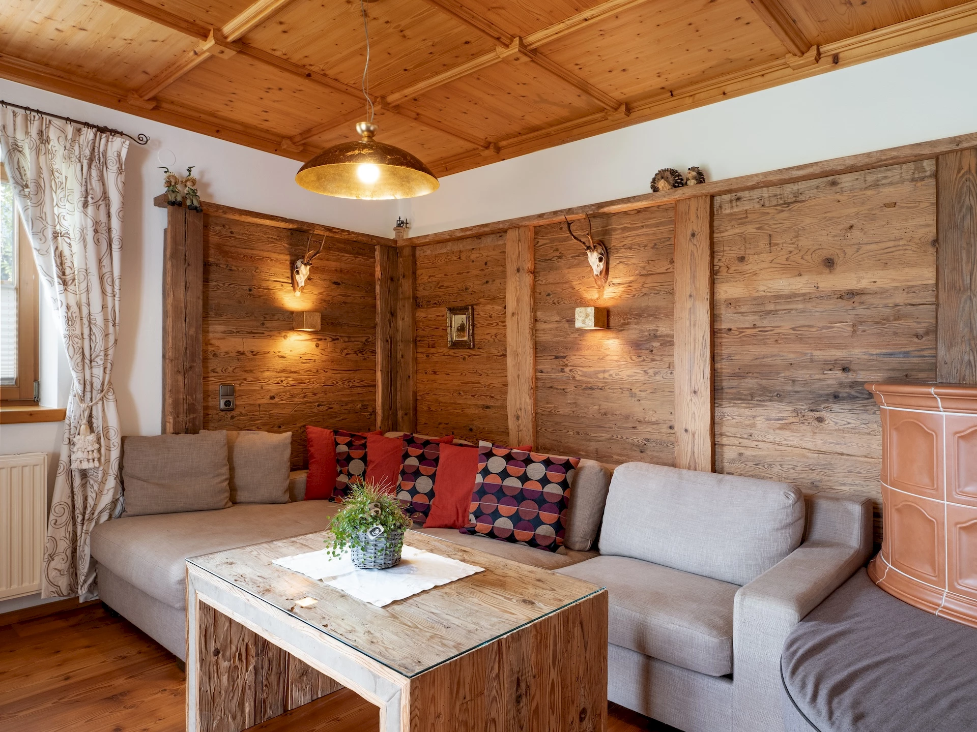 Wohnzimmer mit Sofa und Kachelofen im Erdgeschoss des Tirolerhauses