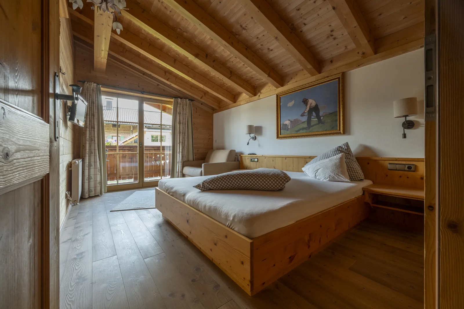 Schlafzimmer mit Zirbenholzbett und Zugang zum Balkon