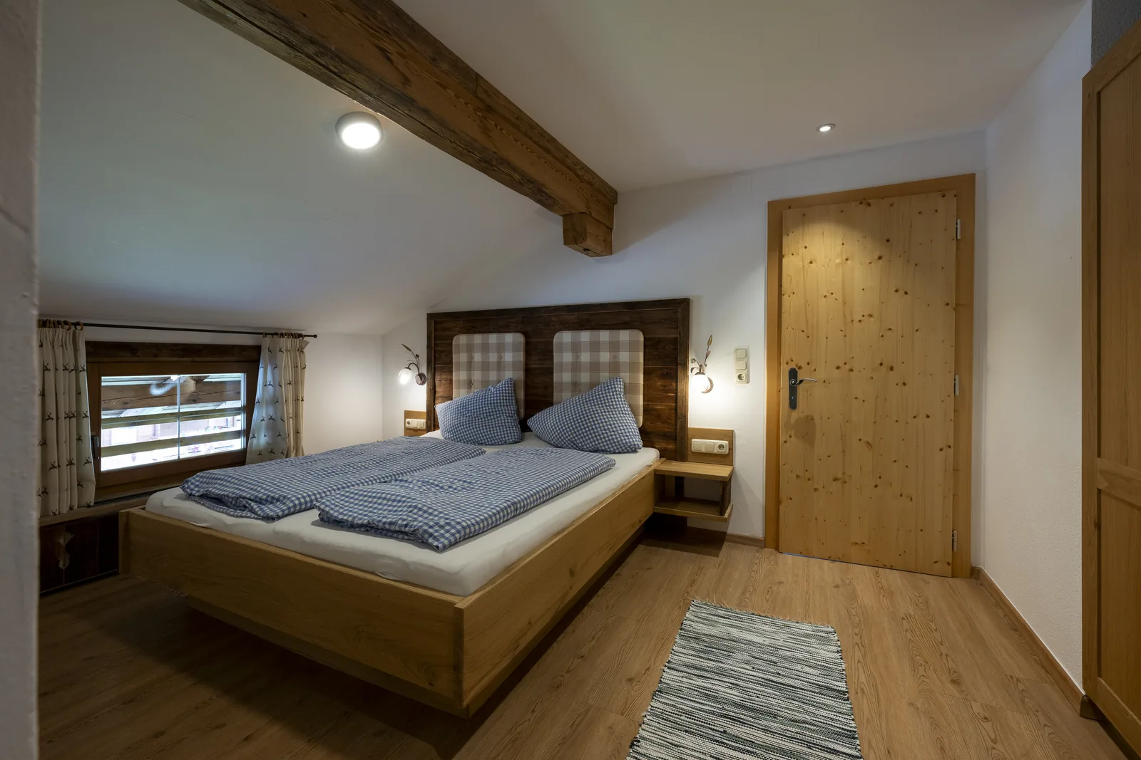 Bedroom in the Alpenblick apartment with a double bed in Swiss stone pine
