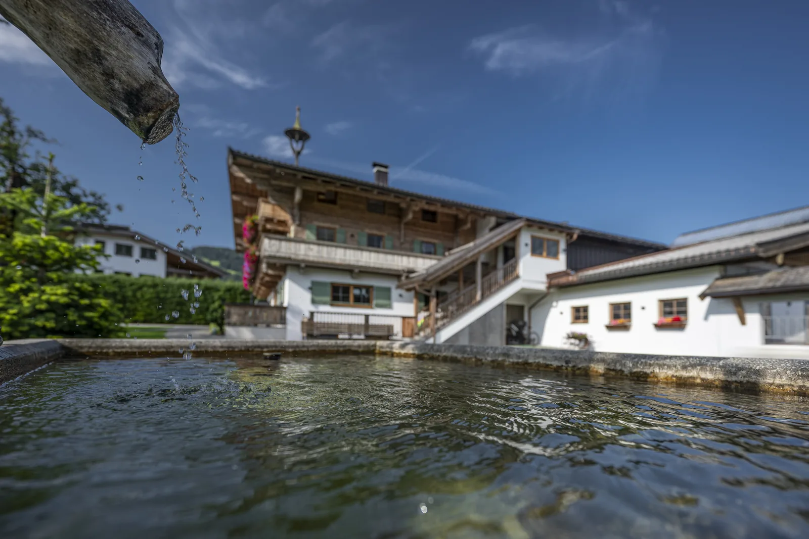 Brunnentrog im Innenhof des Gafalhofs, im Wasser spiegelt sich das Bauernhaus