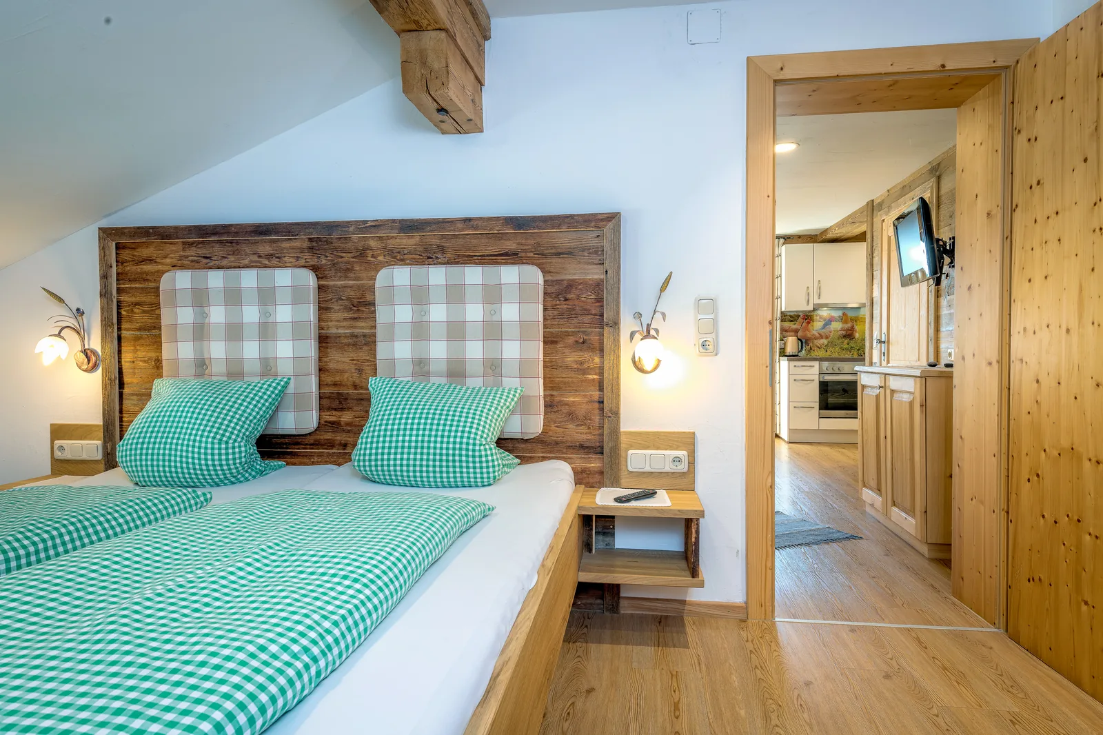 Doppelbett im Alpenblick vor Altholz-Kopfteil mit Blick in Richtung Küche