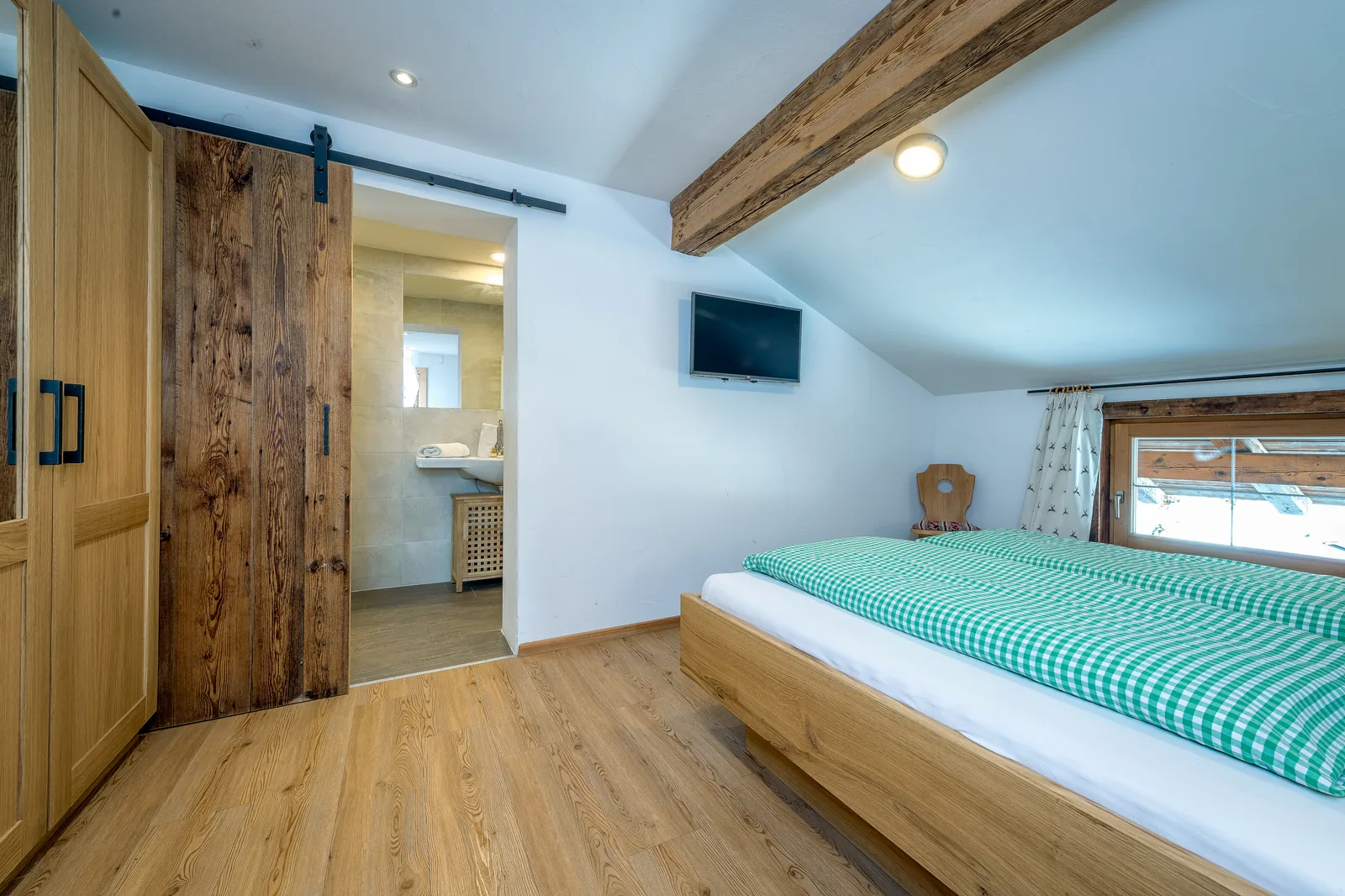 Schlafzimmer im Alpenblick mit Altholz-Schiebetür zum angrenzenden Badezimmer