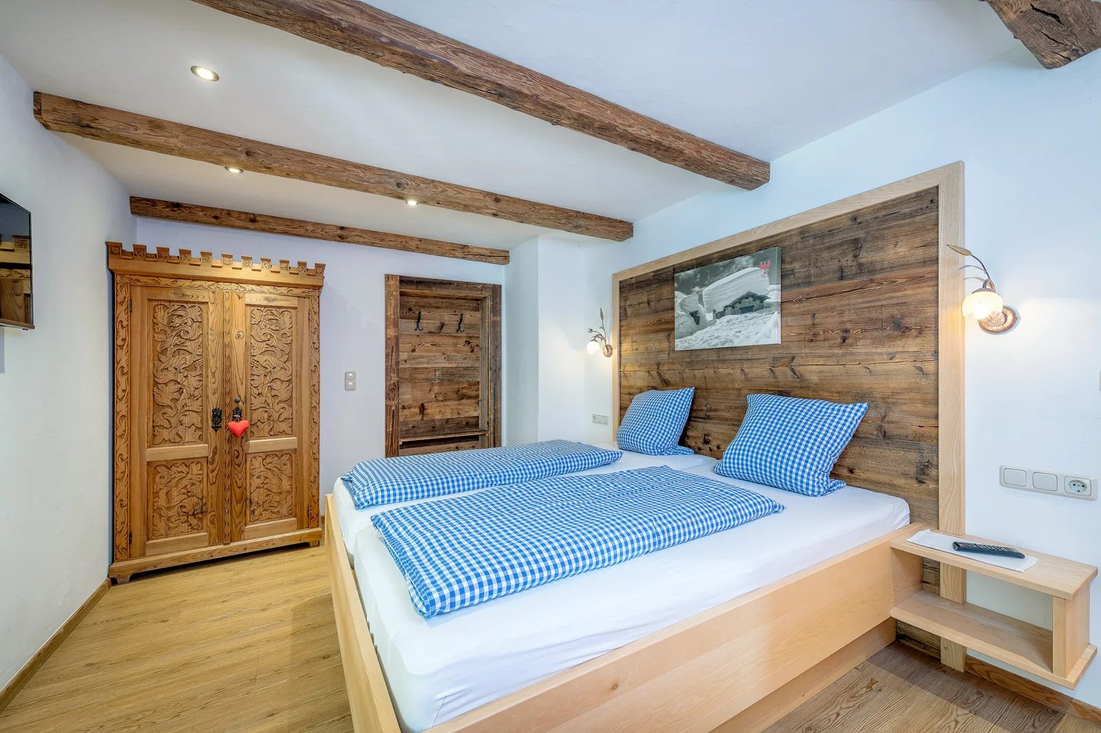 Doppelbett im Astbergblick neben handgeschnitztem Bauernschrank aus Massivholz