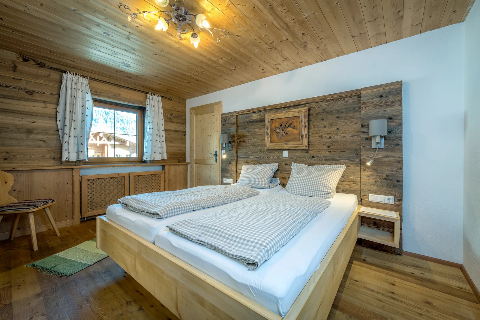 Doppelbett im Kaiserblick vor Altholzwand mit Leselampen und Nachtkästchen