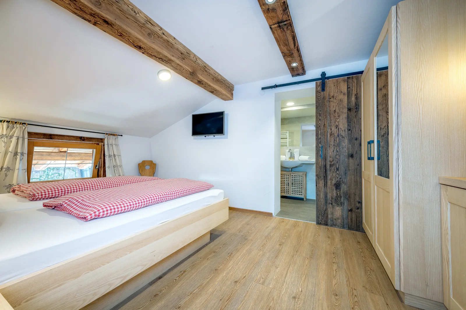 Doppelbett im Sonnblick mit Kleiderschrank und offenen Dachbalken aus Altholz