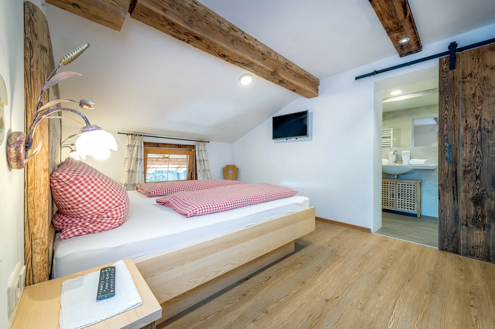 Schlafzimmer der Ferienwohnung Sonnblick mit Altholz-Schiebetür zum Badezimmer