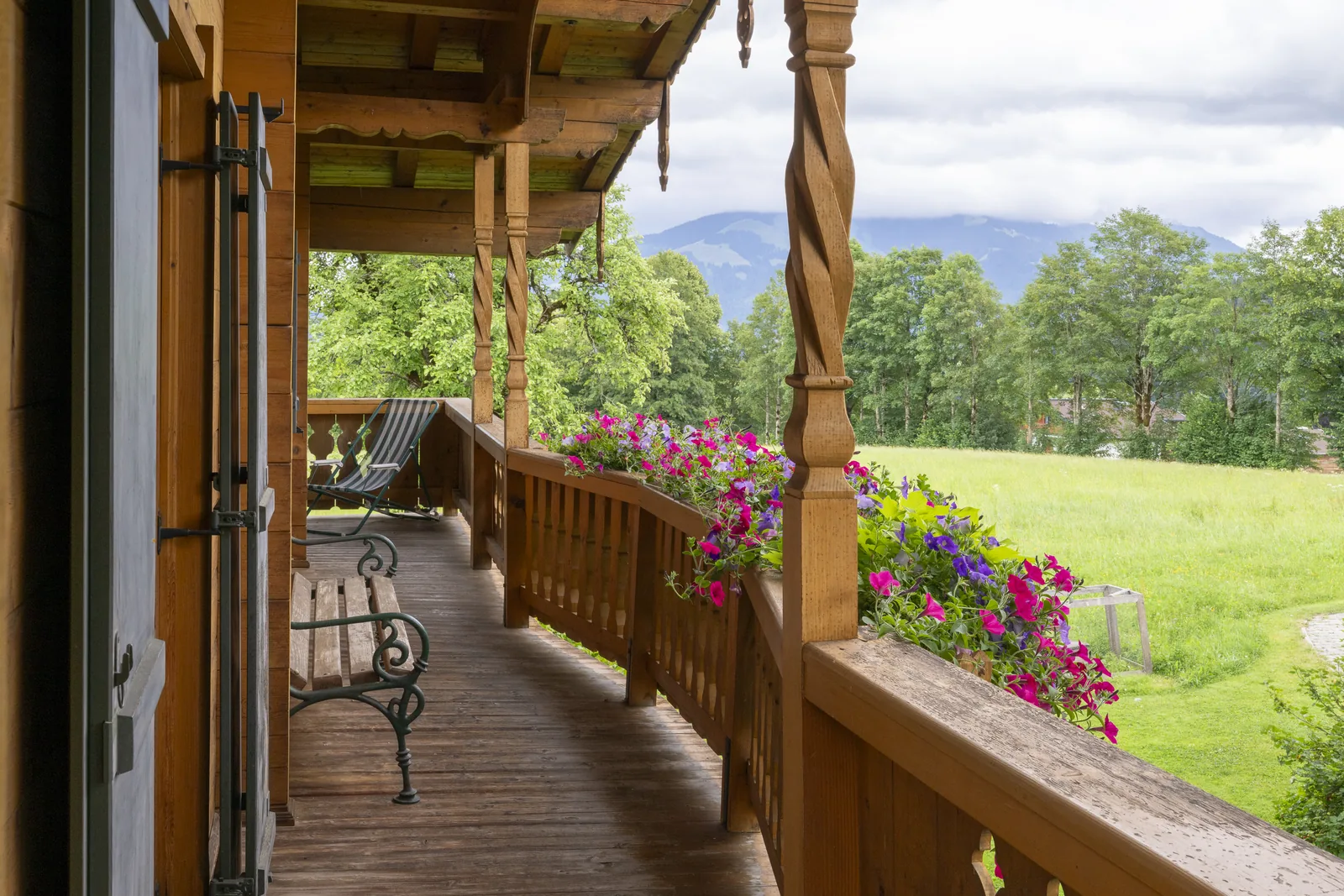 Überdachter Balkon des Tirolerhauses mit Blumen und Sitzbank