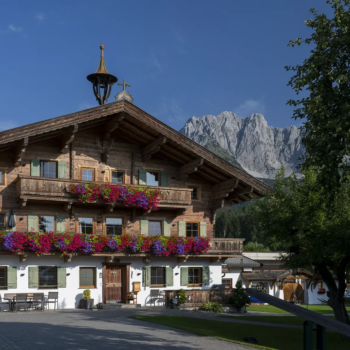 Blumengeschmückte Balkone am Bauernhaus des Gafalhofs vor dem Kaisergebirge